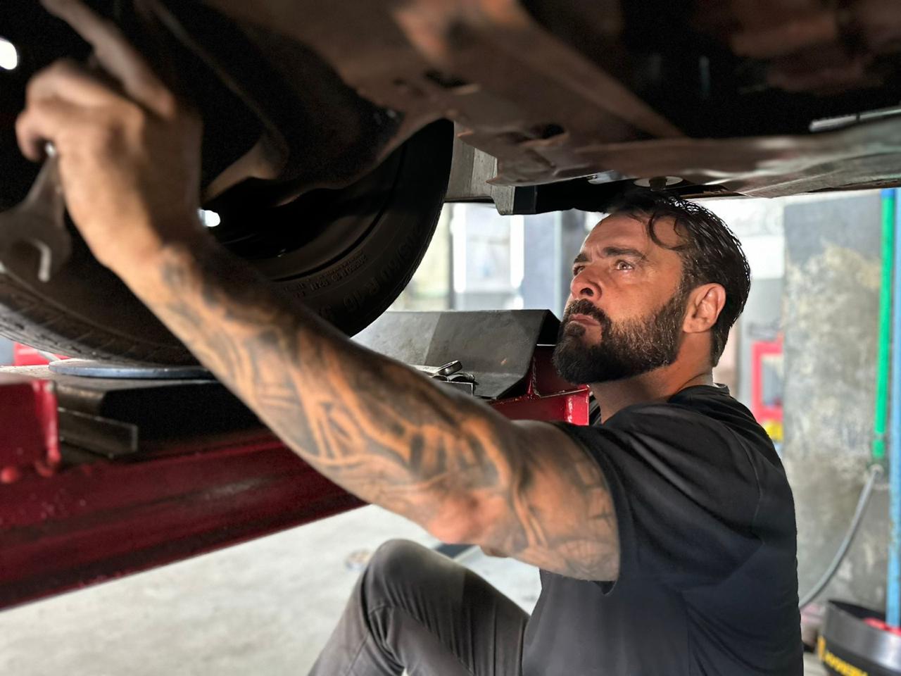 Mecânico realizando serviço na suspensão de um veículo elevado